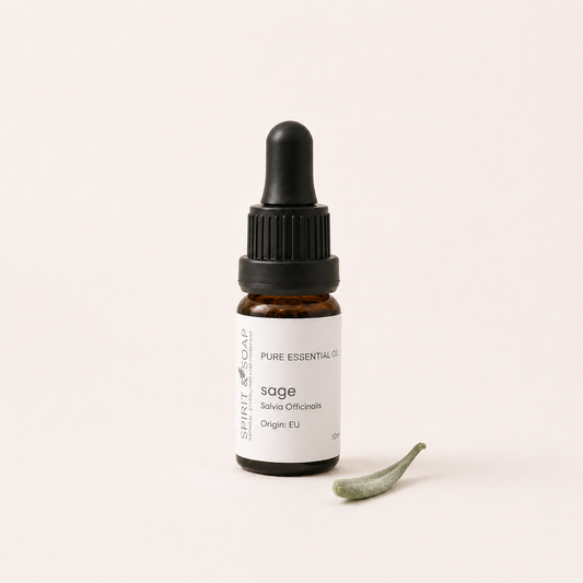 A small amber glass dropper bottle labeled 'sage' by Spirit of Soap, with a black dropper cap and a small green sage sprig beside it on a warm off-white background.